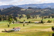 Scenic farmland with a white house and fenced fields