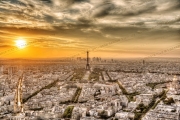 Panoramic view of Paris with the Eiffel Tower at sunset, under a dramatic sky.