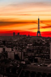 Striking Eiffel Tower silhouette against a fiery sunset sky over Paris rooftops